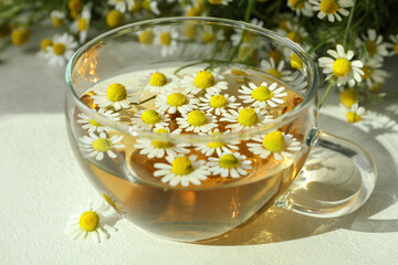 Cup of chamomile tea on white textured table