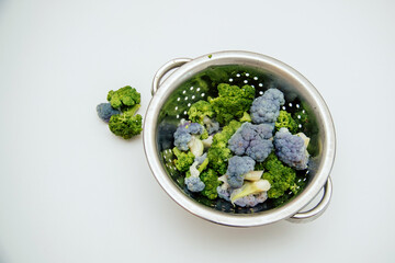 Fresh raw cauliflower in a metal saucepan with water on a light background
