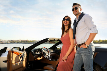 Stylish couple near luxury convertible car outdoors