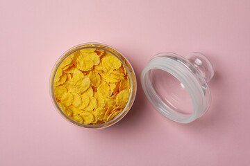 Jar of corn flakes on pink background