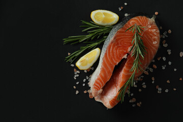 Fresh raw salmon and spices on black background