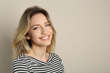 Obraz premium Portrait of happy young woman with beautiful blonde hair and charming smile on beige background. Space for text