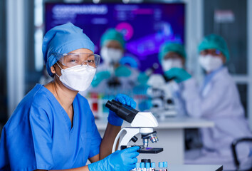Group of female researchers team concentrated on  working with microscope and lab equipment in...