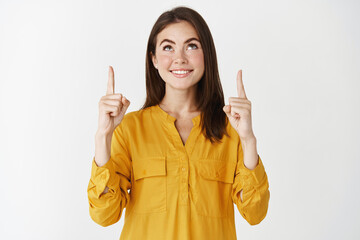 Young happy woman smiling, pointing and looking up at promo offer, concept of shopping and...