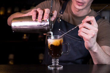 Close up hands of the bartender who make a cocktail. Irish coffee