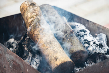 wood logs in barbecue stand, burning and creating smoke and coal