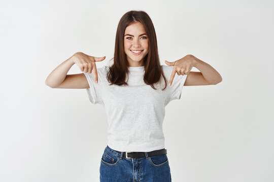 Attractive Smiling Woman Pointing Fingers Down At Promo Banner, Showing Copy Space, Standing Over White Background