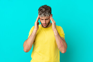 Young handsome caucasian man isolated on blue background with headache