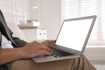 Man with modern laptop indoors, closeup. Space for design