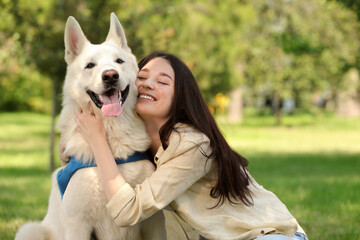Teenage girl hugging her white Swiss Shepherd dog in park