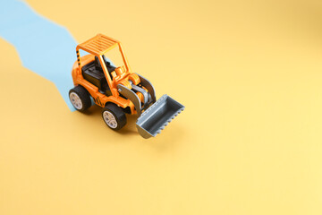 A toy bulldozer with the blue strip at the back.  Work in progress concept.  Image contain blur...