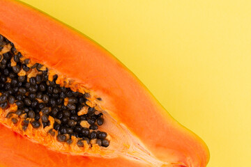 Top view of half ripe papaya fruit with seeds on yellow background, full depth of field. Copy space