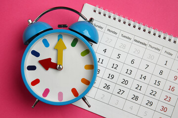 Fototapeta na wymiar Alarm clock and calendar on pink background, flat lay. Reminder concept
