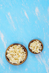 two bowls of popcorn on a blue background. Vertical photo