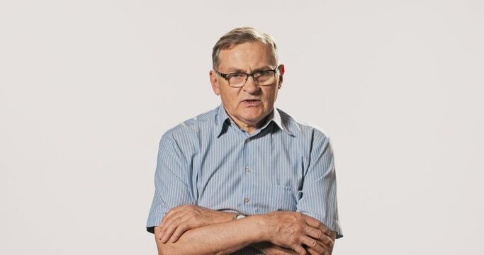 Conversation, interview with elderly man with glasses, school principal, headmaster, doctor, company manager, mature pensioner with gray hair answers questions, sits with crossed arms