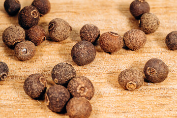 Allspice falls on a wooden surface, close-up, macro.
