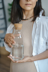 Unrecognizable young woman holding a jug of clean water in her hands. Naturalness, purity and healthy lifestyle concept