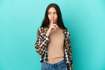 Young French woman isolated on blue background showing a sign of silence gesture putting finger in mouth