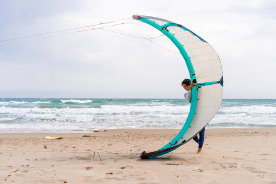 Sportswoman with power kite on shore against stormy sea