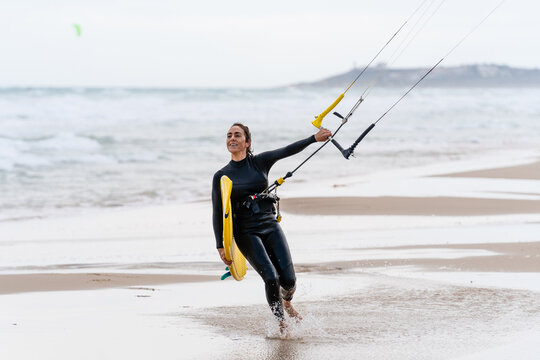 Kitesurfer with kiteboard on sea coast in stormy weather
