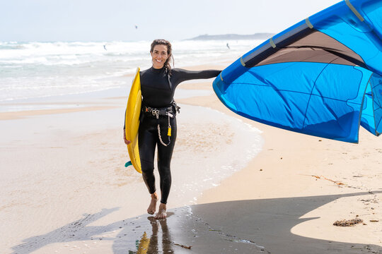 Kitesurfer with power kite walking on sea coast