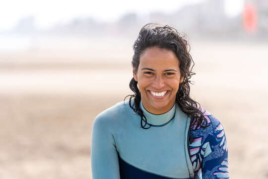 Smiling ethnic kitesurfer with kiteboarding equipment on sea shore