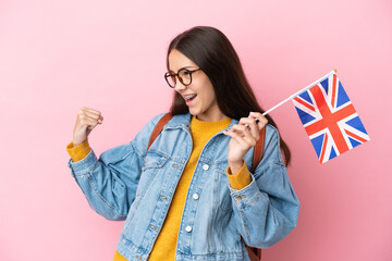 Young French girl holding an United Kingdom flag isolated on pink background celebrating a victory