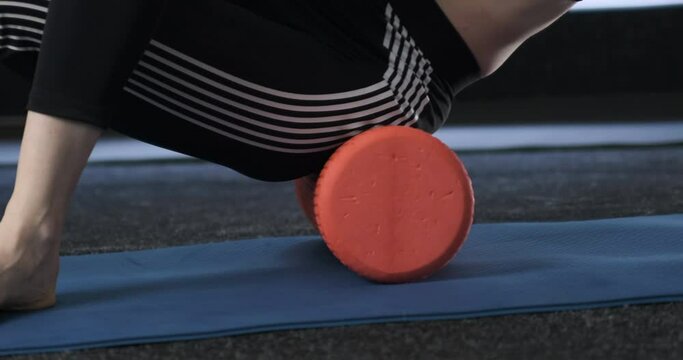 Girl in gym makes myofascial massage hips with roller. Sports woman engaged in physiotherapy with foam roller
