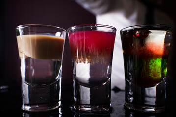 Barman preparing cocktail shots at the bar counter. Barman mixing drinks at the night club.