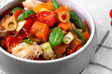 Salad with baked vegetables, croutons, olives, capers, cherry tomatoes and olive oil served in the gray bowl. Mediterranean meal