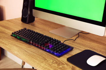 Modern computer and RGB keyboard on wooden table indoors