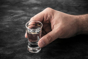 Hand with a glass of vodka. Alcoholism concept.