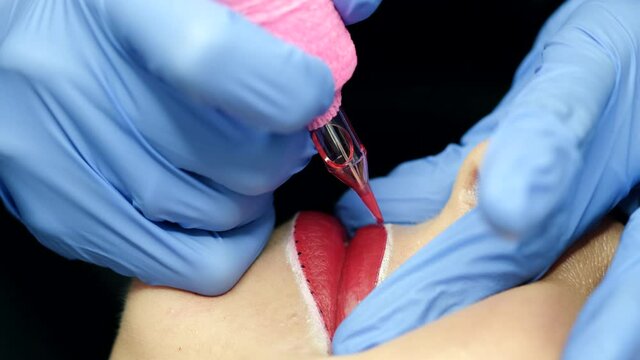 Micro pigmentation of lips process. Female permanent make up master holding machine applying pigment of woman client lips. Beauty and aesthetic treatment concept