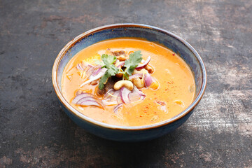 Massaman curry in an oriental bowl, on a black stony background. Thai curry based on cashew nut paste, cardamom, cinnamon and coconut milk with pieces of lamb meat and tofu. Fusion cousine.