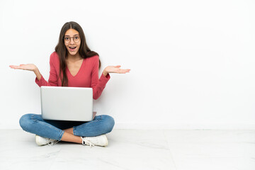 Young French girl sitting on the floor with her laptop with shocked facial expression