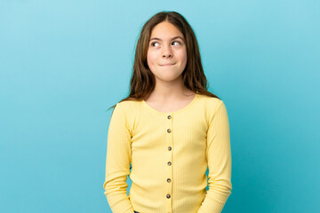 Fototapeta premium Little caucasian girl isolated on blue background having doubts while looking up