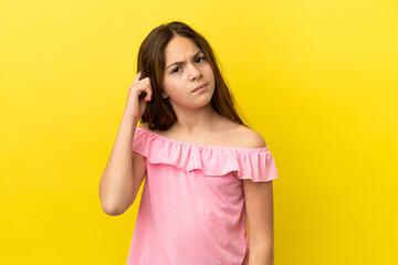 Little caucasian girl isolated on yellow background having doubts