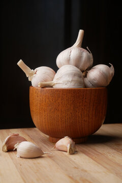  garlic in a wooden bowl on black background,