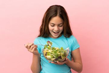 Little caucasian girl isolated on pink background holding a bowl of salad with happy expression