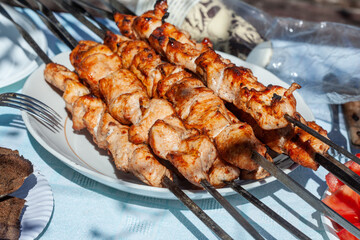 freshly cooked chicken skewers lying in a disposable plastic plate with fried bread
