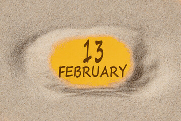 February 13. 13th day of the month, calendar date. Hole in sand. Yellow background is visible through hole. Winter month, day of the year concept