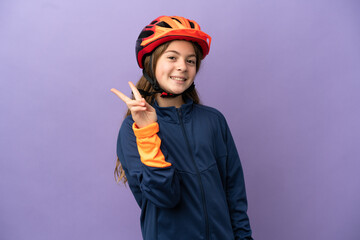Little caucasian girl isolated on purple background smiling and showing victory sign