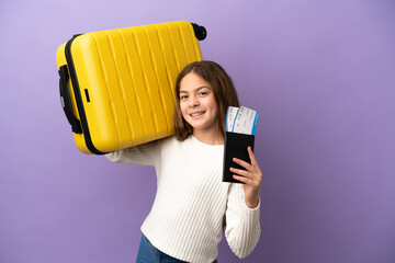 Little caucasian girl isolated on purple background in vacation with suitcase and passport