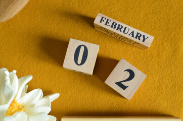 February 2, Wooden Calendar cube on yellow felt fabric with peony flower for date icon background.