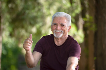 Pensioner points his finger ok and rests in the park