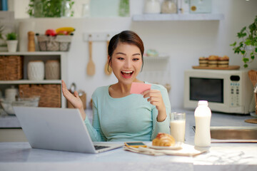 young surprised wondered woman using laptop computer, buying with credit bank card, smiling.