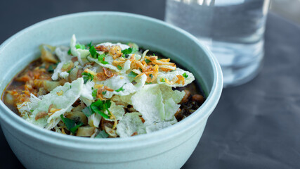 Close up on a bowl of chicken porridge in a bowl on a black background