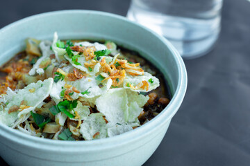 Close up on a bowl of chicken porridge in a bowl on a black background