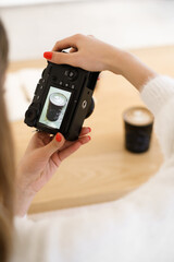 Woman hand taking picture of coffee on the table. Blogger taking lifestyle photo for social media. Black laptop screen