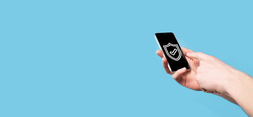 Male hand holding protect shield with a check mark icon on blue background. Protection network security computer and safe your data concept .